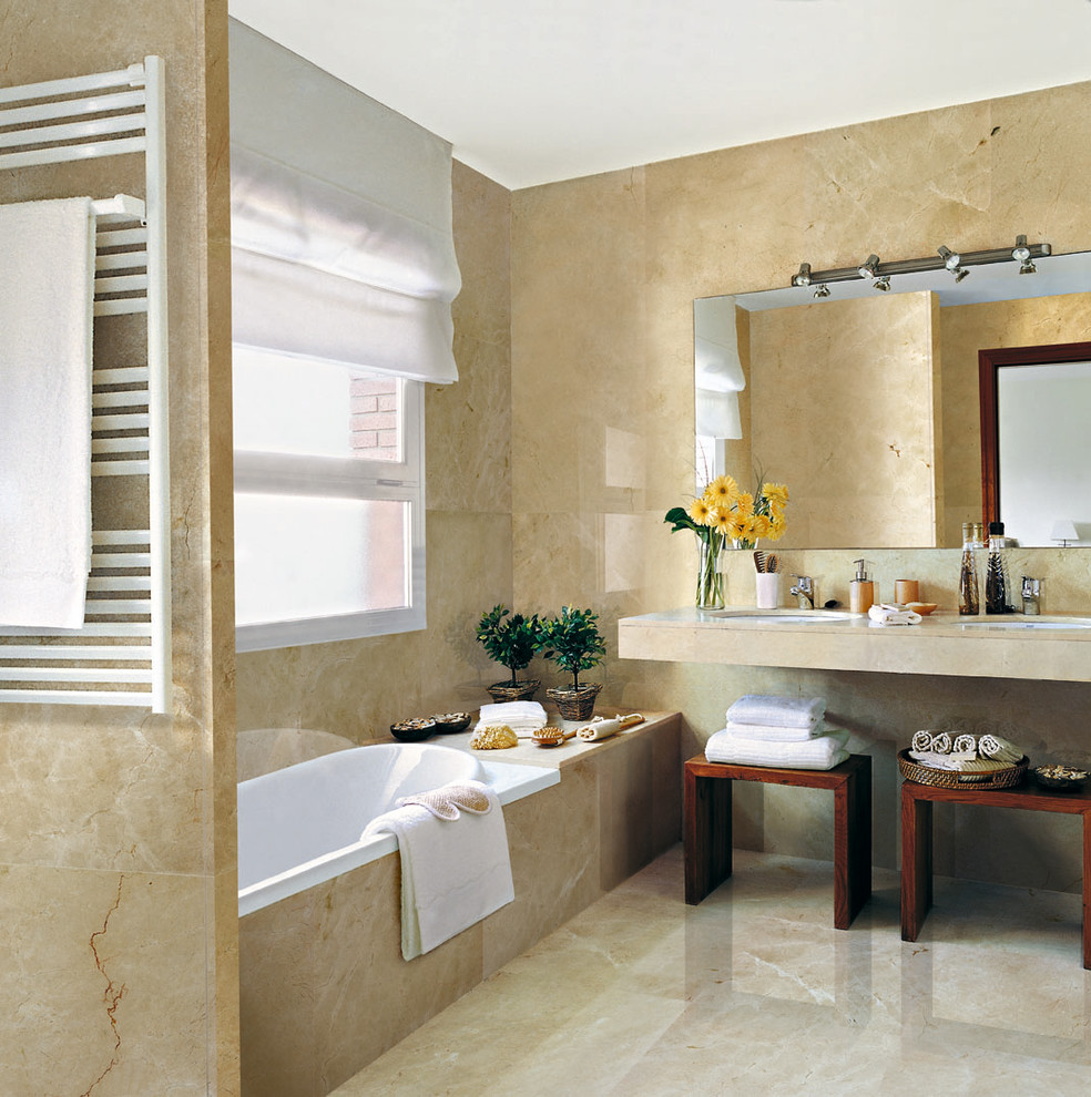 This is an example of a mid-sized transitional master bathroom in Other with a drop-in tub, beige tile, stone slab, beige walls, marble floors, an undermount sink and marble benchtops.