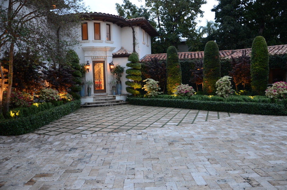 Inspiration for a mid-sized transitional front yard partial sun formal garden for summer in Miami with brick pavers.