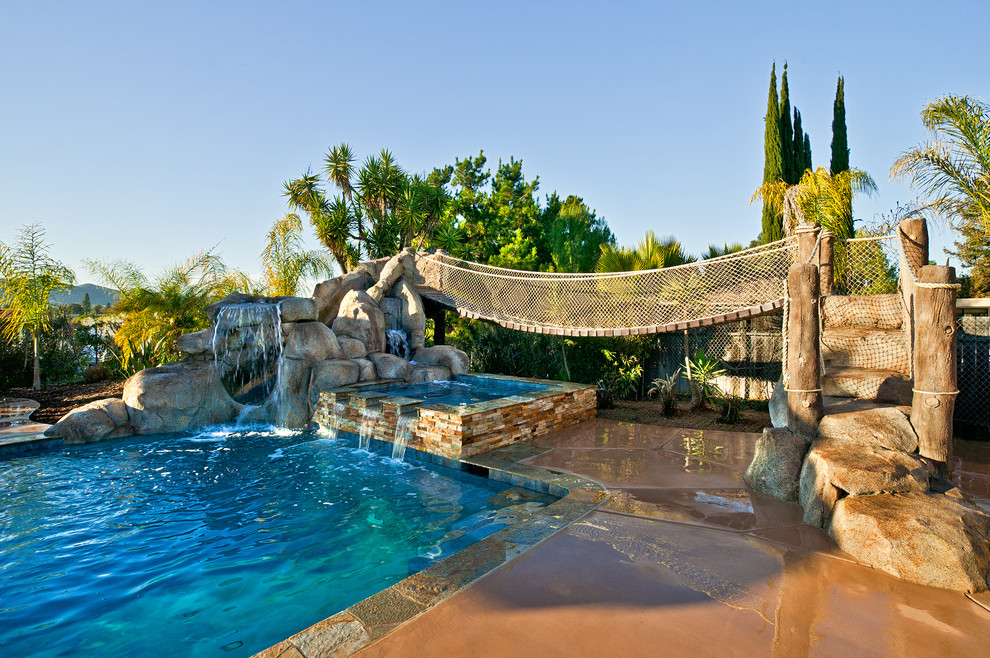 This is an example of a mid-sized tropical backyard rectangular lap pool in San Diego with a water slide and concrete slab.