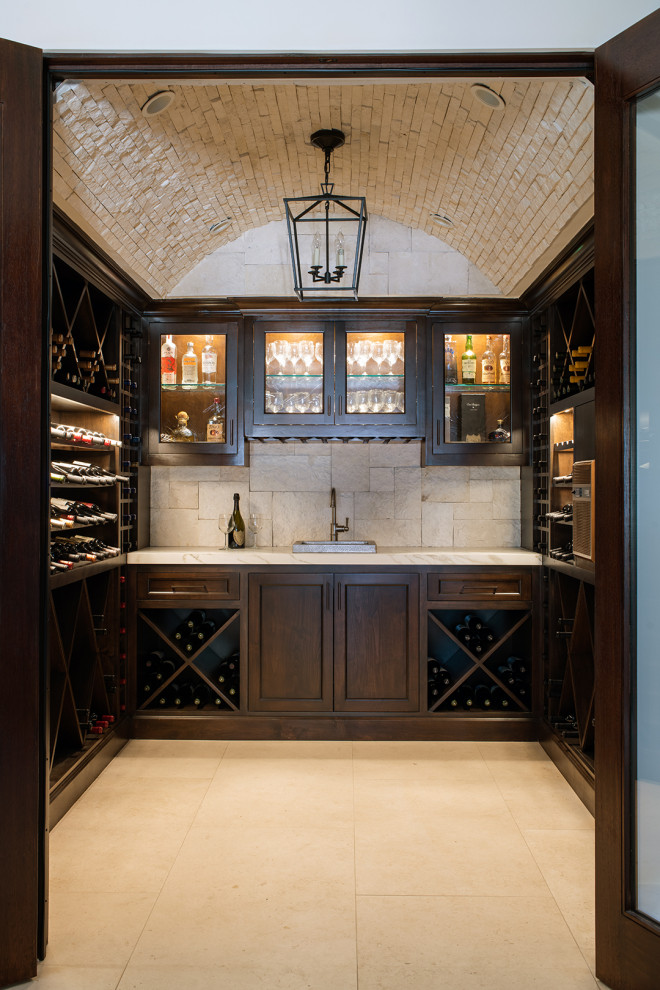 This is an example of a mid-sized mediterranean wine cellar in Los Angeles with limestone floors, diamond bins and beige floor.
