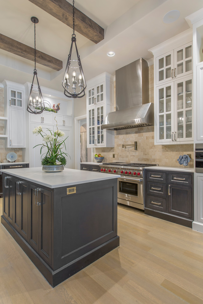 This is an example of a transitional open plan kitchen in Dallas with recessed-panel cabinets, grey cabinets, quartz benchtops, beige splashback, travertine splashback, panelled appliances, light hardwood floors, multiple islands, beige floor and white benchtop.