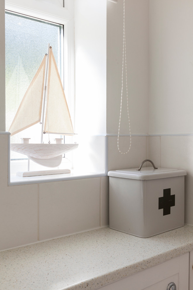 Inspiration for a small beach style kids bathroom in London with recessed-panel cabinets, white cabinets, a corner shower, a one-piece toilet, white tile, ceramic tile, white walls, linoleum floors, a drop-in sink and laminate benchtops.