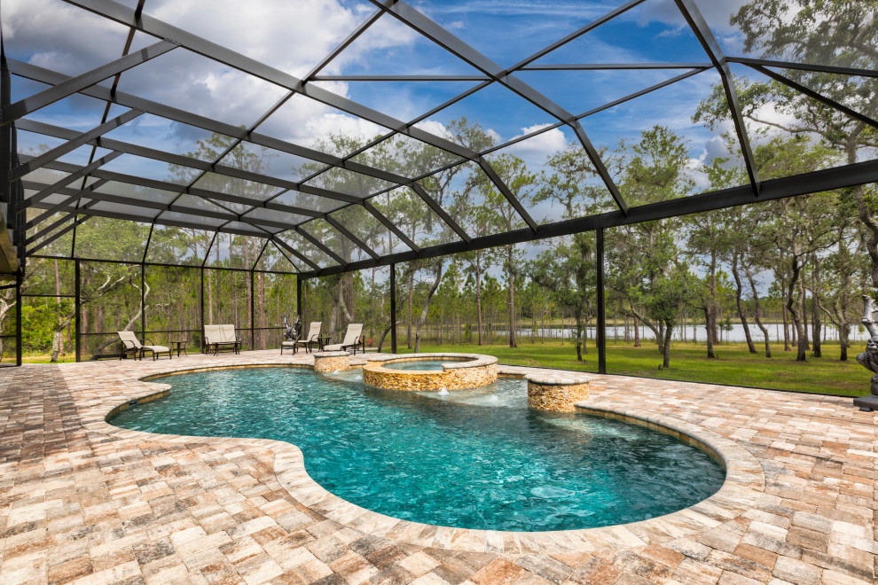 Idée de décoration pour une piscine naturelle et arrière champêtre sur mesure avec un bain bouillonnant et des pavés en pierre naturelle.