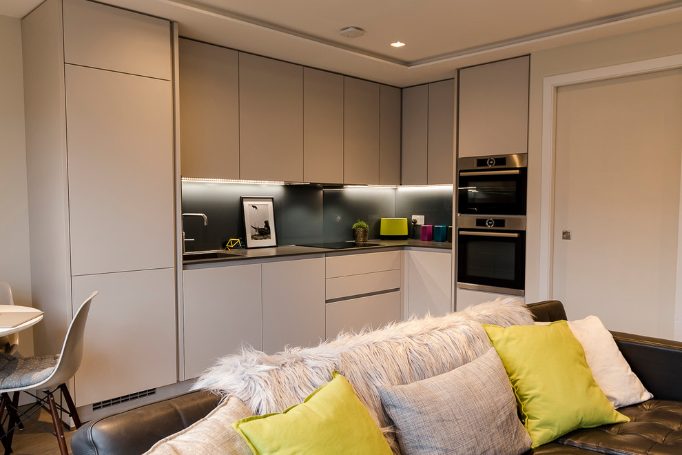 Photo of a small contemporary open plan kitchen in London with solid surface benchtops and panelled appliances.