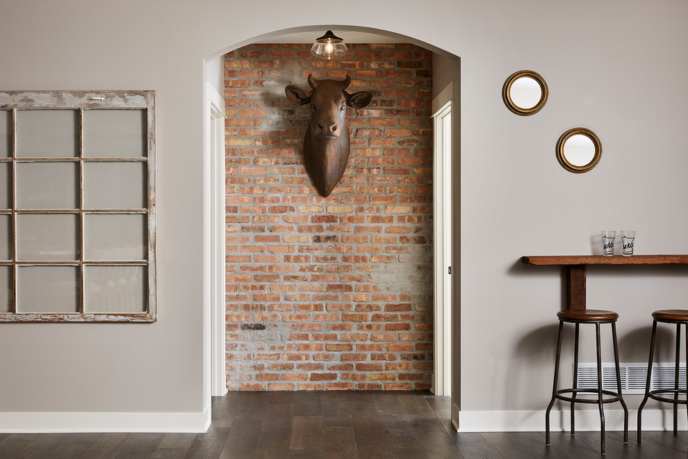 Photo of a large industrial walk-out basement in Minneapolis with grey walls, vinyl floors, a corner fireplace, a brick fireplace surround and brown floor.