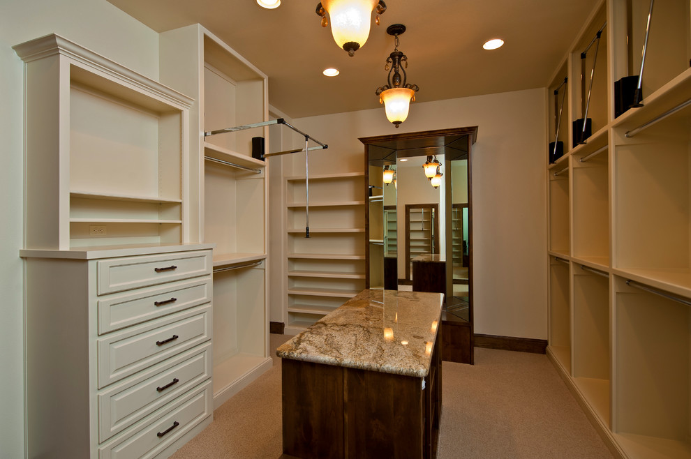 Inspiration for an expansive mediterranean gender-neutral walk-in wardrobe in Austin with white cabinets and carpet.
