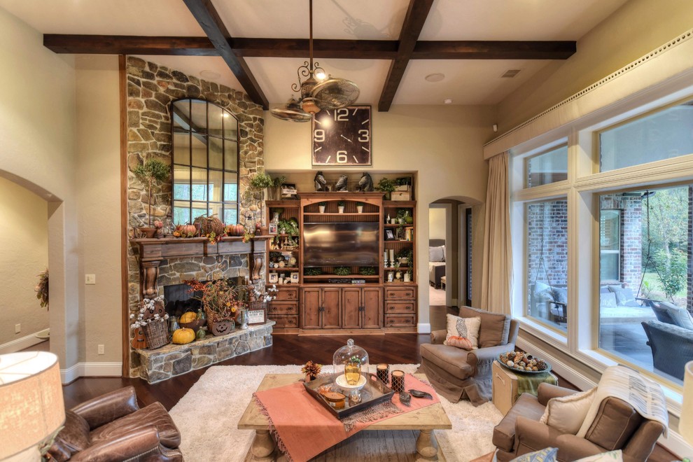 This is an example of a mid-sized eclectic open concept living room in Houston with beige walls, dark hardwood floors, a corner fireplace, a stone fireplace surround and a built-in media wall.