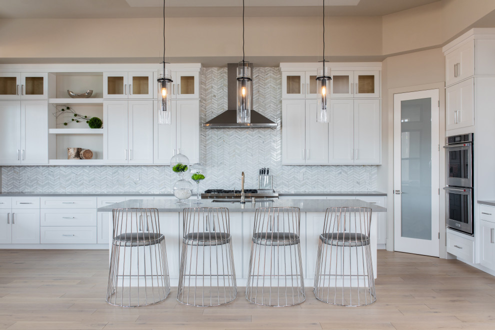 Mid-sized transitional galley light wood floor, beige floor and coffered ceiling eat-in kitchen photo in Sacramento with an undermount sink, shaker cabinets, white cabinets, quartz countertops, white backsplash, marble backsplash, stainless steel appliances, an island and gray countertops