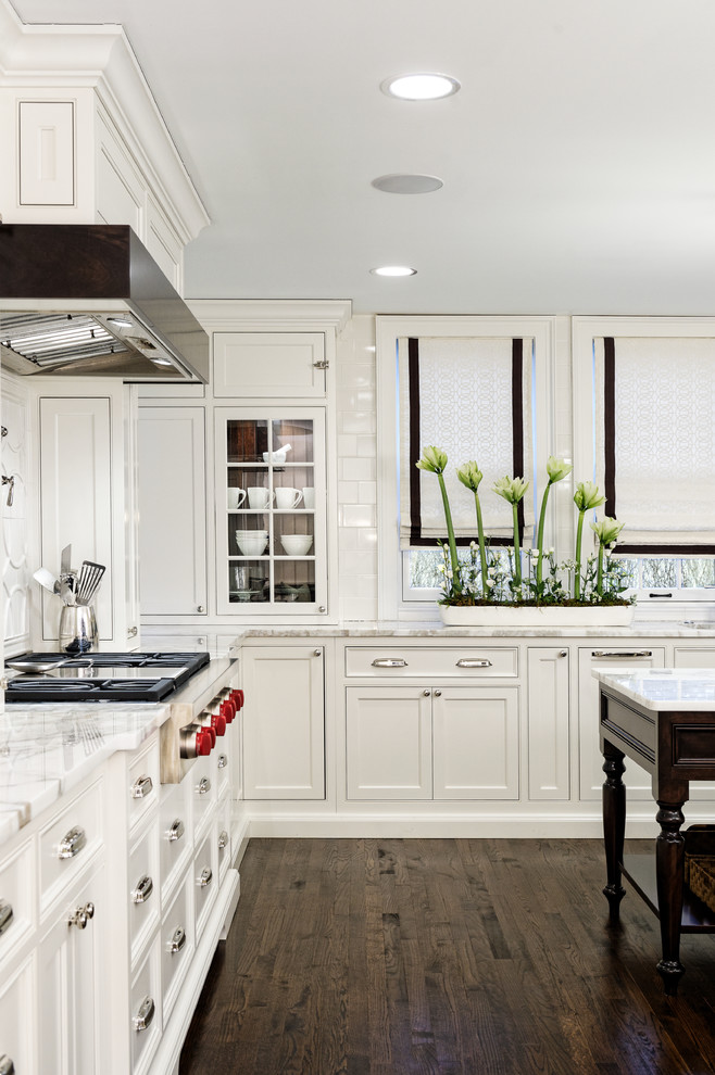 Kitchen - traditional u-shaped dark wood floor kitchen idea in Cleveland with an undermount sink, white cabinets, marble countertops, white backsplash, ceramic backsplash and paneled appliances