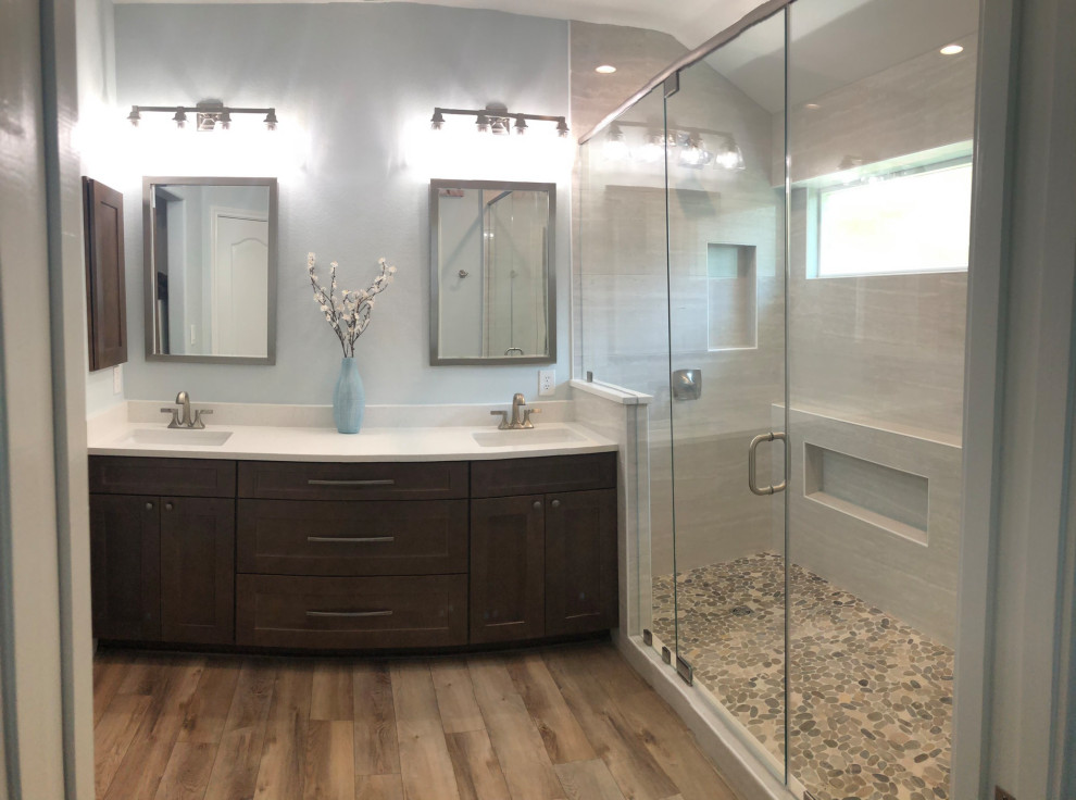 Photo of a mid-sized transitional master bathroom in Austin with shaker cabinets, brown cabinets, a double shower, a one-piece toilet, gray tile, ceramic tile, blue walls, vinyl floors, an undermount sink, engineered quartz benchtops, brown floor, a hinged shower door, white benchtops, a double vanity and a built-in vanity.