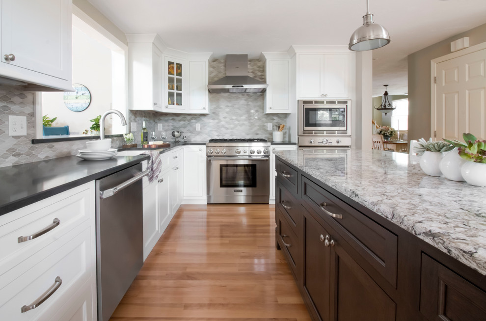Inspiration for a mid-sized traditional l-shaped eat-in kitchen in Boston with an undermount sink, shaker cabinets, white cabinets, grey splashback, stone tile splashback, stainless steel appliances, light hardwood floors, with island, brown floor and quartz benchtops.