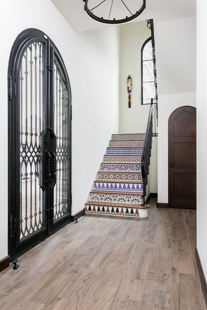 Photo of a mid-sized mediterranean wood u-shaped staircase in Orange County with terracotta risers and metal railing.