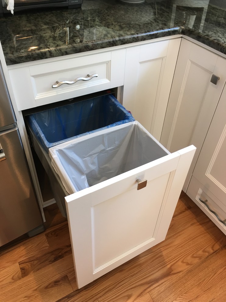 Enclosed kitchen - mid-sized transitional l-shaped light wood floor enclosed kitchen idea with an undermount sink, flat-panel cabinets, white cabinets, granite countertops, white backsplash, subway tile backsplash, stainless steel appliances and no island