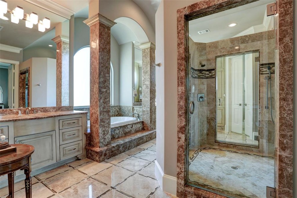 This is an example of a large mediterranean master bathroom in Houston with furniture-like cabinets, distressed cabinets, a drop-in tub, an alcove shower, pink tile, marble, pink walls, marble floors, an undermount sink, granite benchtops, beige floor, a hinged shower door and pink benchtops.