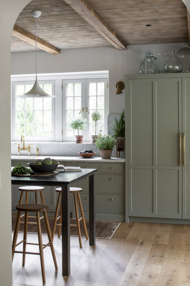 Inspiration för vitt kök, med en undermonterad diskho, släta luckor, gröna skåp, stänkskydd i marmor, mellanmörkt trägolv och en köksö