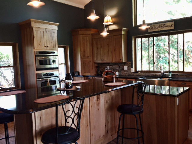 Mountain style u-shaped eat-in kitchen photo with a farmhouse sink, recessed-panel cabinets, light wood cabinets, granite countertops, multicolored backsplash, stainless steel appliances and an island
