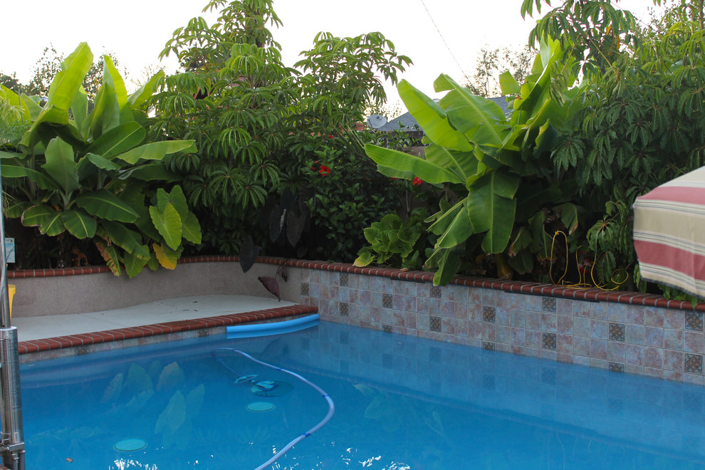 Photo of a mid-sized beach style backyard custom-shaped pool in Orange County with a hot tub and brick pavers.