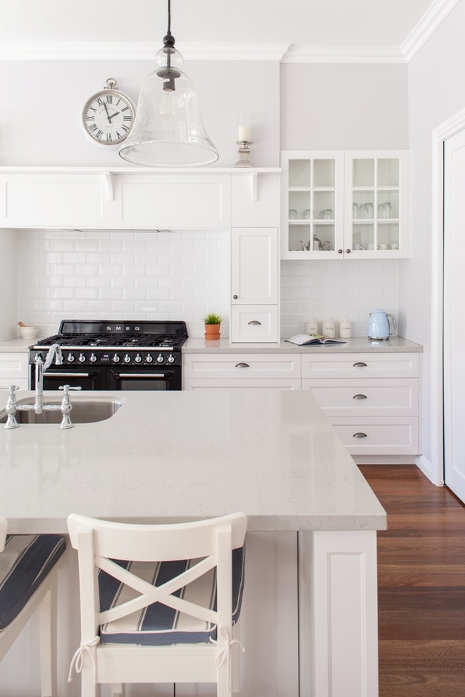 Design ideas for a traditional kitchen in Brisbane with an undermount sink, glass-front cabinets, white cabinets, black appliances, dark hardwood floors and with island.