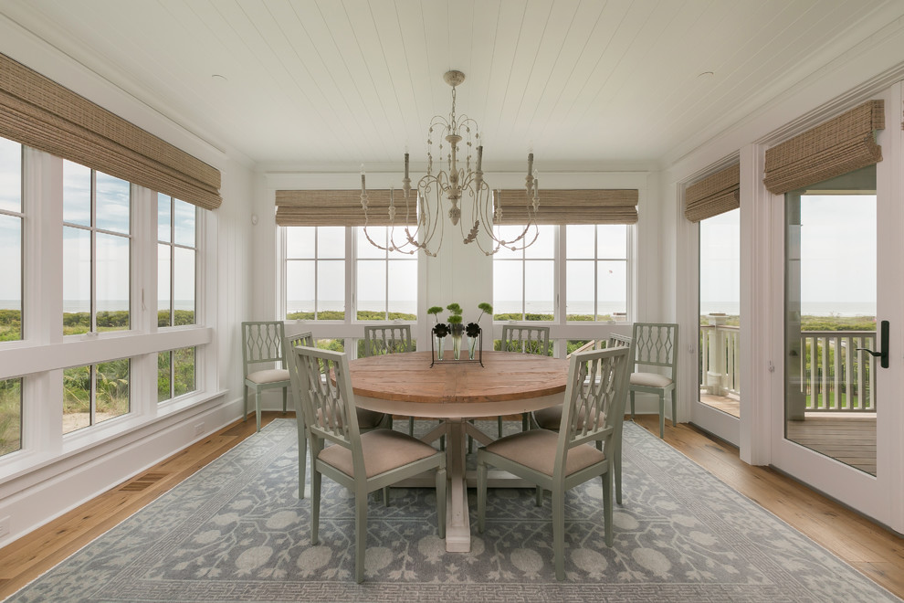 Beach style dining room in Charleston with white walls and light hardwood floors.
