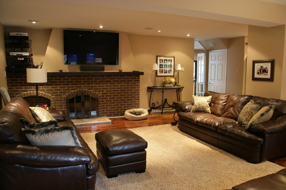 This is an example of a large traditional open concept family room in Montreal with beige walls, a standard fireplace, a brick fireplace surround and a wall-mounted tv.