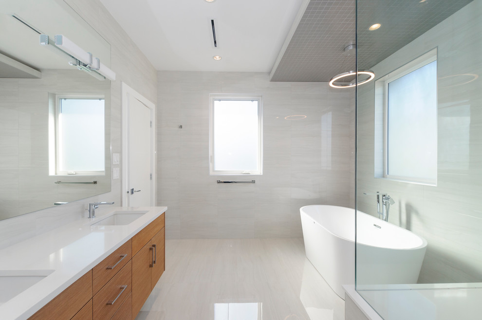 Mid-sized transitional master bathroom in Vancouver with flat-panel cabinets, medium wood cabinets, a freestanding tub, a corner shower, a one-piece toilet, white tile, porcelain tile, white walls, porcelain floors, an undermount sink, engineered quartz benchtops, white floor, a hinged shower door and white benchtops.