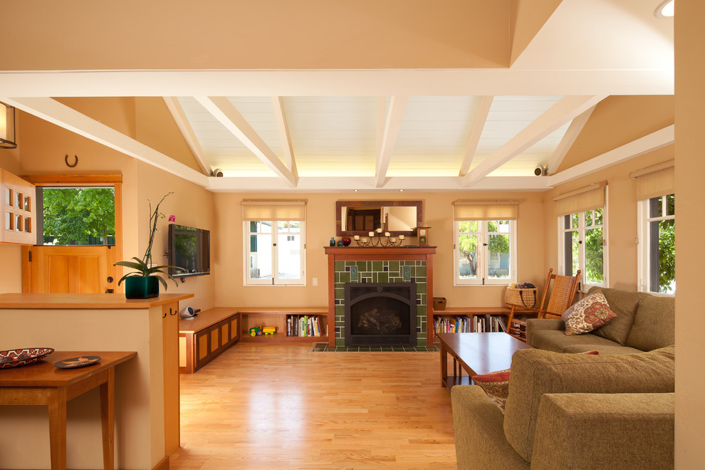 Design ideas for a large arts and crafts open concept living room in San Luis Obispo with a library, beige walls, a standard fireplace, a tile fireplace surround, light hardwood floors, a wall-mounted tv and brown floor.