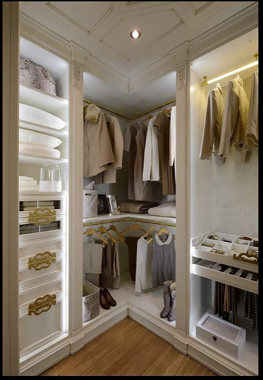 This is an example of a mid-sized gender-neutral storage and wardrobe in New York with recessed-panel cabinets, white cabinets, light hardwood floors, white floor and wood.
