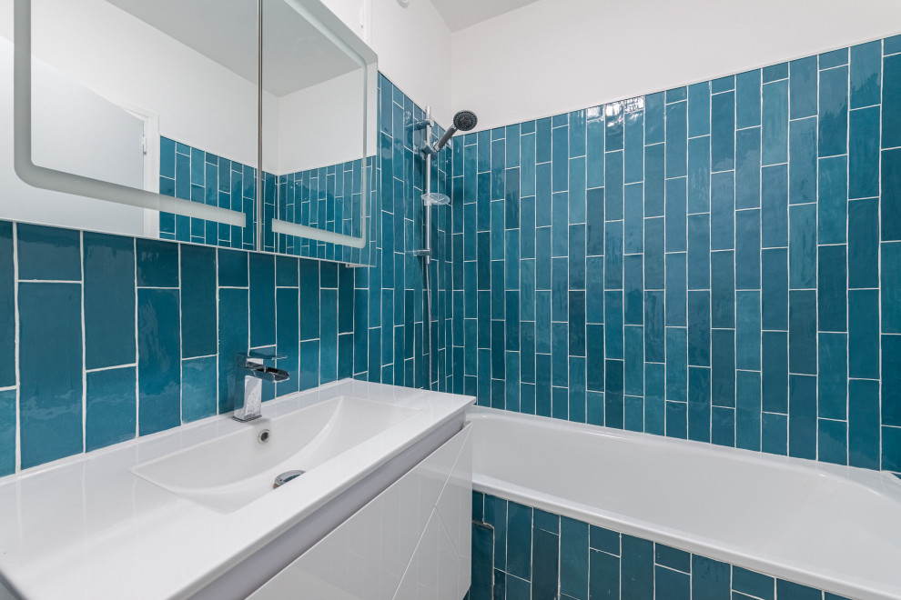 Источник вдохновения для домашнего уюта: ванная комната среднего размера со стиральной машиной в современном стиле с белыми фасадами, полновстраиваемой ванной, душем над ванной, синей плиткой, керамической плиткой, белыми стенами, врезной раковиной и тумбой под одну раковину