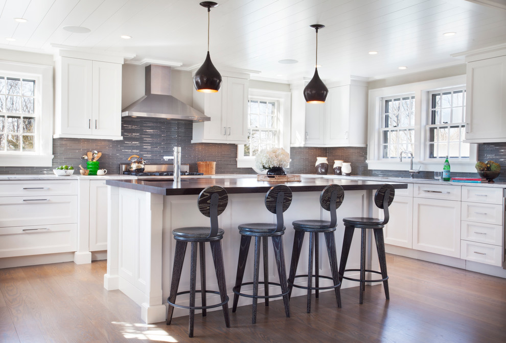 Inspiration for a mid-sized transitional u-shaped medium tone wood floor eat-in kitchen remodel with an undermount sink, recessed-panel cabinets, white cabinets, granite countertops, gray backsplash, glass tile backsplash and stainless steel appliances