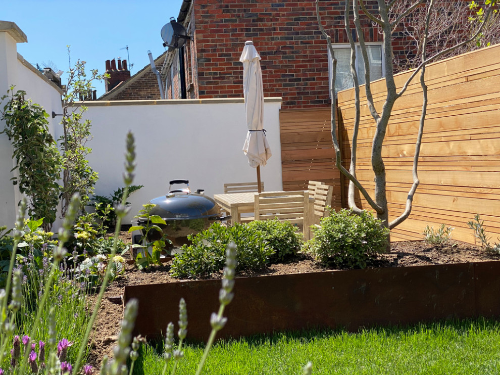 Mid-sized contemporary backyard full sun xeriscape in Sussex with with raised garden bed and a wood fence for summer.