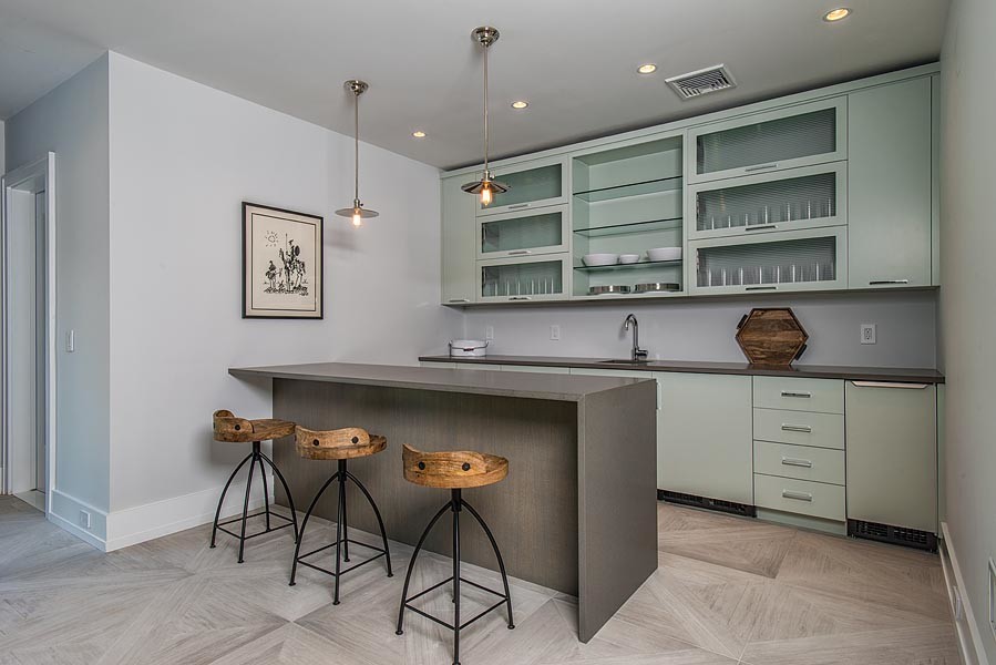 Inspiration for a transitional single-wall seated home bar in New York with flat-panel cabinets, green cabinets, concrete benchtops, light hardwood floors and beige floor.