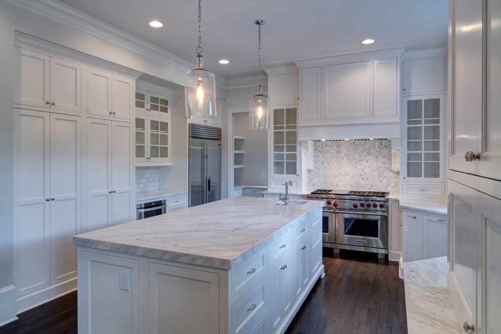 Photo of a large transitional u-shaped separate kitchen in Atlanta with recessed-panel cabinets, white cabinets, marble benchtops, grey splashback, stone tile splashback, stainless steel appliances, dark hardwood floors and with island.