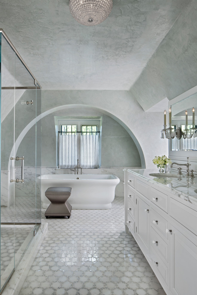 Inspiration for a large transitional master white tile marble floor freestanding bathtub remodel with raised-panel cabinets, white cabinets, marble countertops, an undermount sink and gray walls