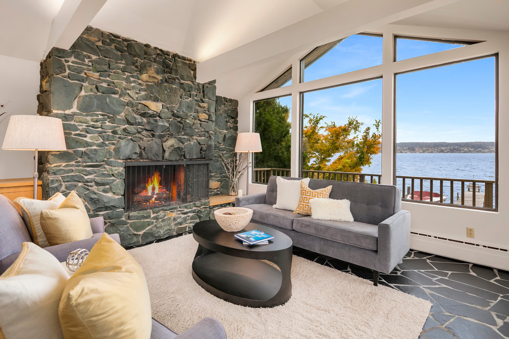 Large midcentury open concept living room in Seattle with white walls, slate floors, a standard fireplace, a stone fireplace surround and black floor.