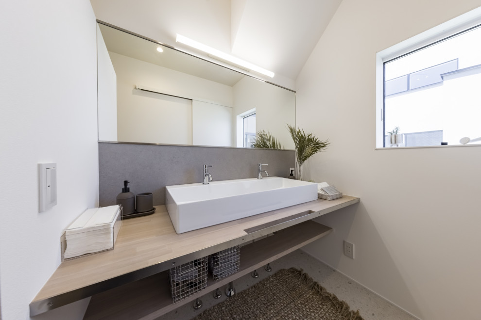 Inredning av ett klassiskt beige beige toalett, med öppna hyllor, beige skåp, vit kakel, vita väggar, vinylgolv, ett fristående handfat, träbänkskiva och vitt golv
