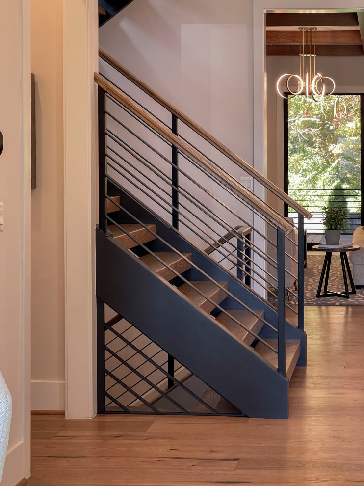 Immagine di una grande scala a rampa dritta design con pedata in legno, parapetto in materiali misti e pannellatura