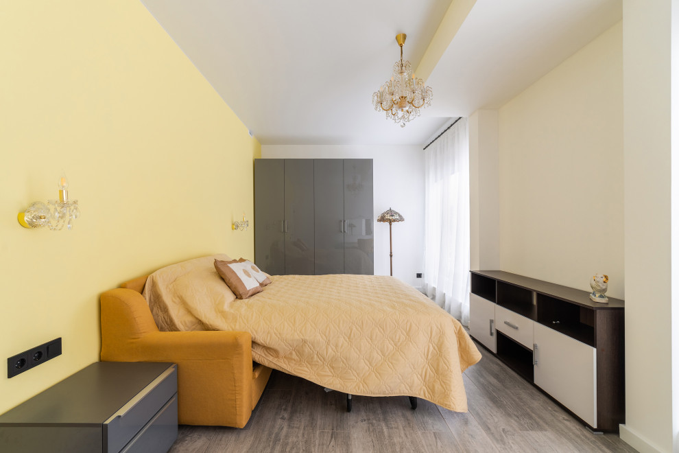 Пример оригинального дизайна: большая хозяйская спальня в стиле модернизм с желтыми стенами, полом из ламината, коричневым полом, многоуровневым потолком и акцентной стеной без камина