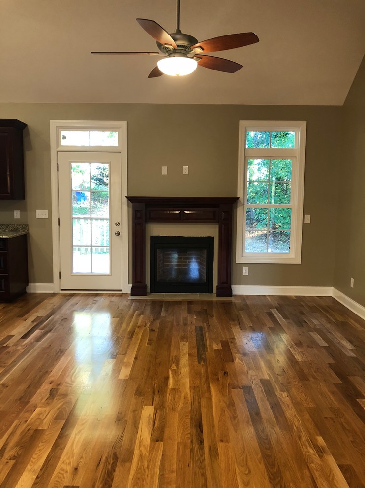 Inspiration for a large arts and crafts formal open concept living room in Charlotte with brown walls, medium hardwood floors, a standard fireplace, a wood fireplace surround, no tv and brown floor.