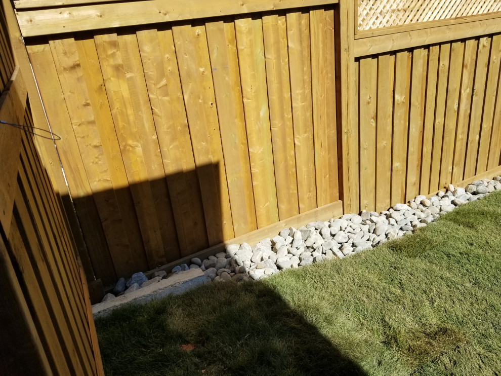 На фото: участок и сад среднего размера на заднем дворе с покрытием из гальки и с деревянным забором с