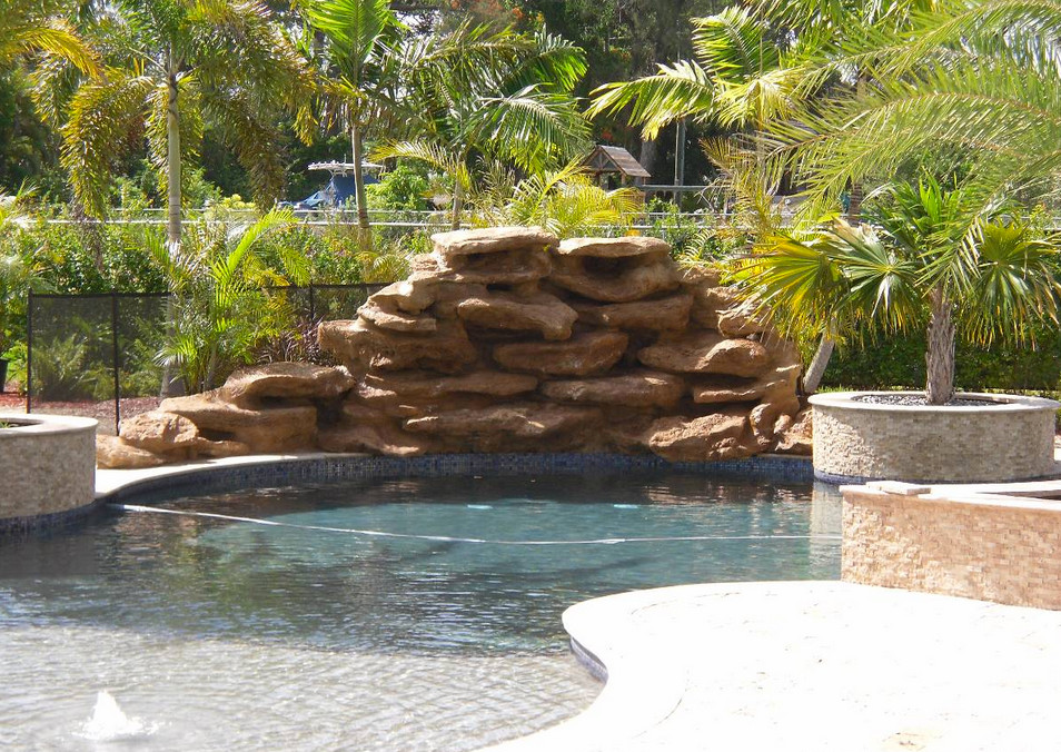 Pool fountain - transitional backyard stone natural pool fountain idea in Miami