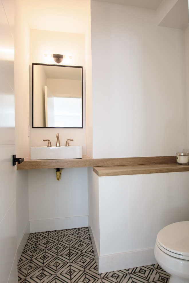 Kleine Moderne Gästetoilette mit braunen Schränken, Toilette mit Aufsatzspülkasten, weißer Wandfarbe, Zementfliesen für Boden, Aufsatzwaschbecken, Waschtisch aus Holz, schwarzem Boden, brauner Waschtischplatte und eingebautem Waschtisch in Denver