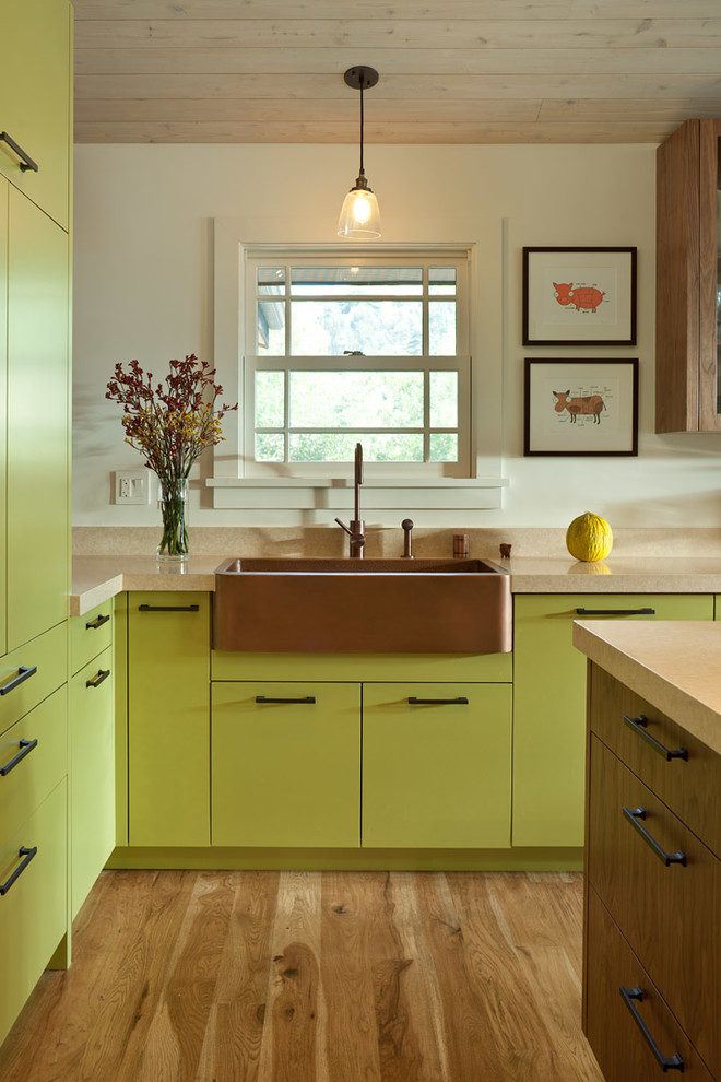 This is an example of a mid-sized traditional u-shaped eat-in kitchen in San Francisco with a farmhouse sink, green cabinets, with island, stainless steel appliances and light hardwood floors.