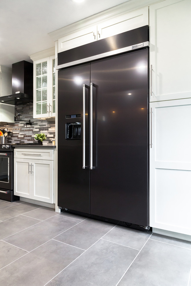 Mid-sized transitional l-shaped porcelain tile and gray floor open concept kitchen photo in Phoenix with an undermount sink, shaker cabinets, white cabinets, quartz countertops, gray backsplash, glass tile backsplash, black appliances, an island and gray countertops