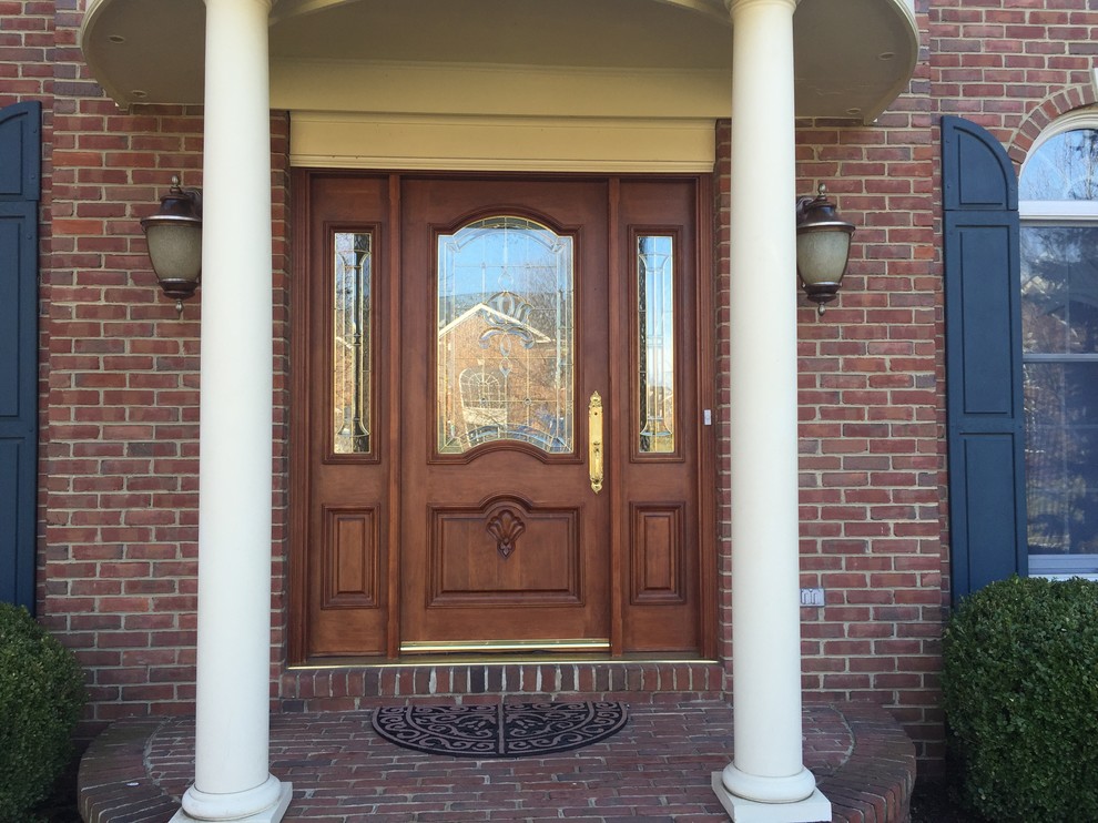 This is an example of a large traditional front door in DC Metro with red walls, brick floors, a double front door, a dark wood front door and red floor.