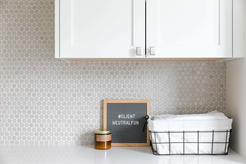Utility room - mid-sized transitional l-shaped porcelain tile and gray floor utility room idea in Calgary with an undermount sink, shaker cabinets, white cabinets, quartzite countertops, white walls, a side-by-side washer/dryer and white countertops