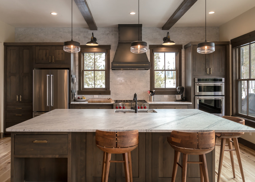 Open concept kitchen - large rustic l-shaped light wood floor and beige floor open concept kitchen idea in Denver with an undermount sink, shaker cabinets, dark wood cabinets, quartz countertops, beige backsplash, subway tile backsplash, stainless steel appliances, an island and white countertops