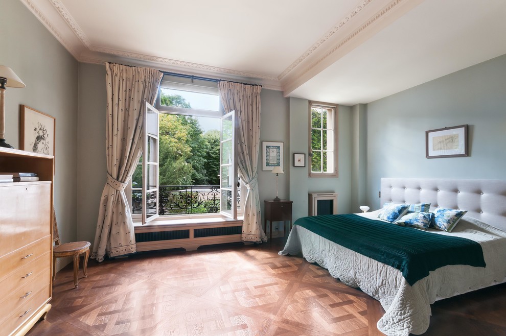 This is an example of a traditional master bedroom in Paris with blue walls, medium hardwood floors and no fireplace.