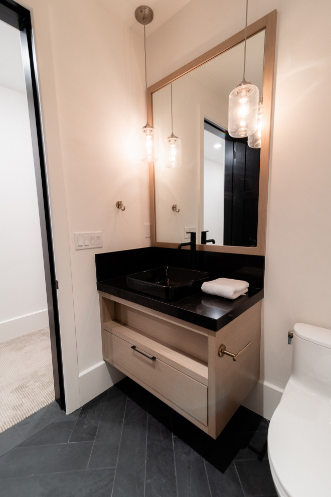 Kleine Moderne Gästetoilette mit flächenbündigen Schrankfronten, beigen Schränken, Toilette mit Aufsatzspülkasten, weißer Wandfarbe, Schieferboden, Aufsatzwaschbecken, Quarzit-Waschtisch, schwarzem Boden, schwarzer Waschtischplatte und schwebendem Waschtisch in Salt Lake City
