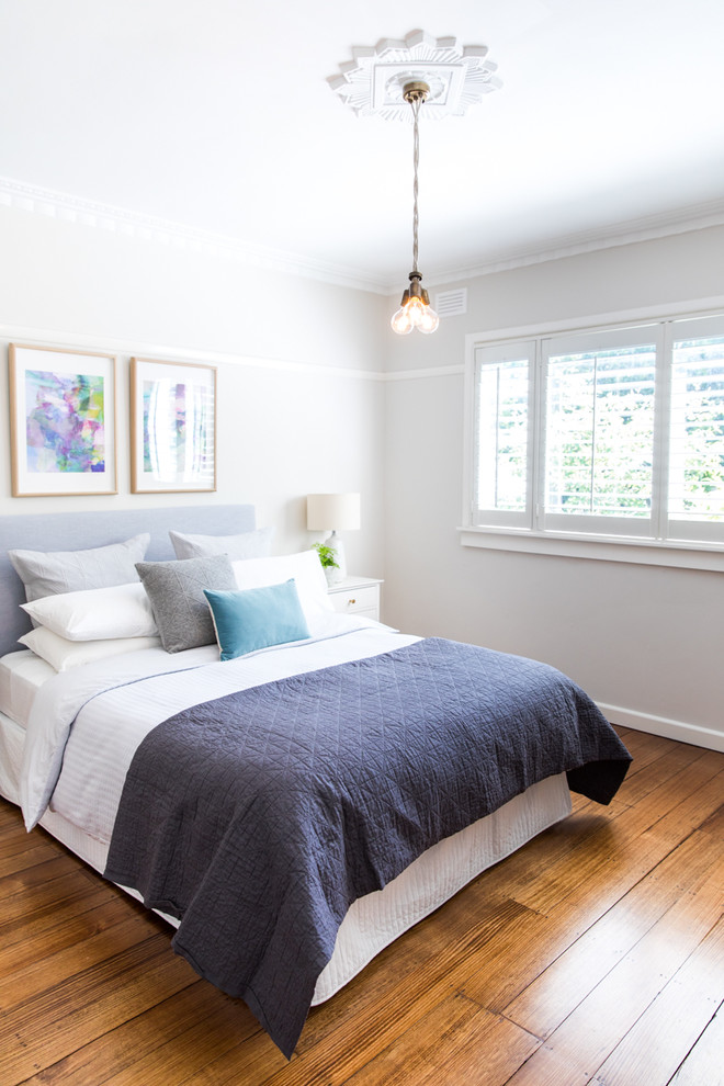 Design ideas for a mid-sized transitional master bedroom in Melbourne with beige walls and medium hardwood floors.