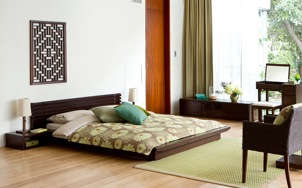 Modelo de dormitorio principal asiático sin chimenea con suelo de madera clara y paredes blancas